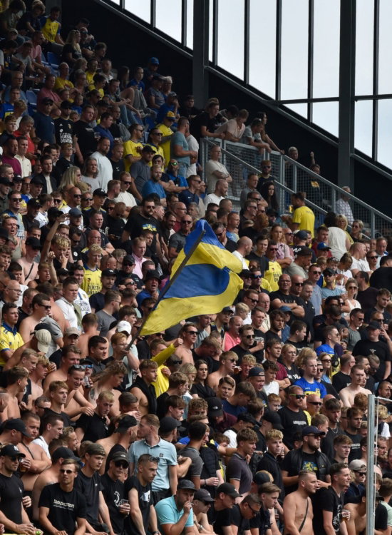 Volle tribune met supporters en vlaggen