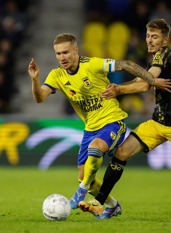 Speler in geel in duel om de bal
