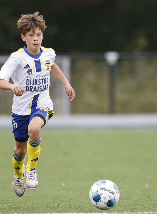 Jeugdspeler in wit uitshirt met bal