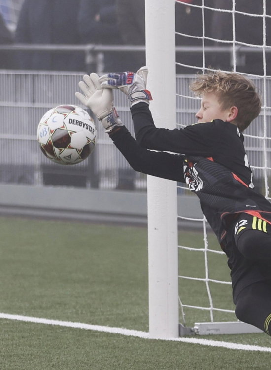 Jeugdkeeper duikt naar de bal