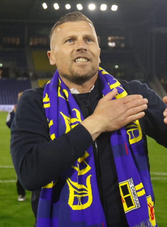 Trainer met sjaal bedankt het publiek