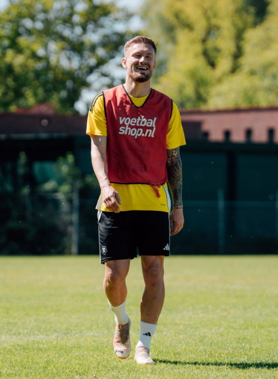Jeugdspeler in rood hesje op het veld