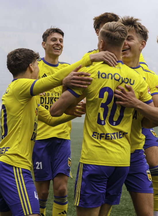 Spelers vieren een doelpunt in de mist