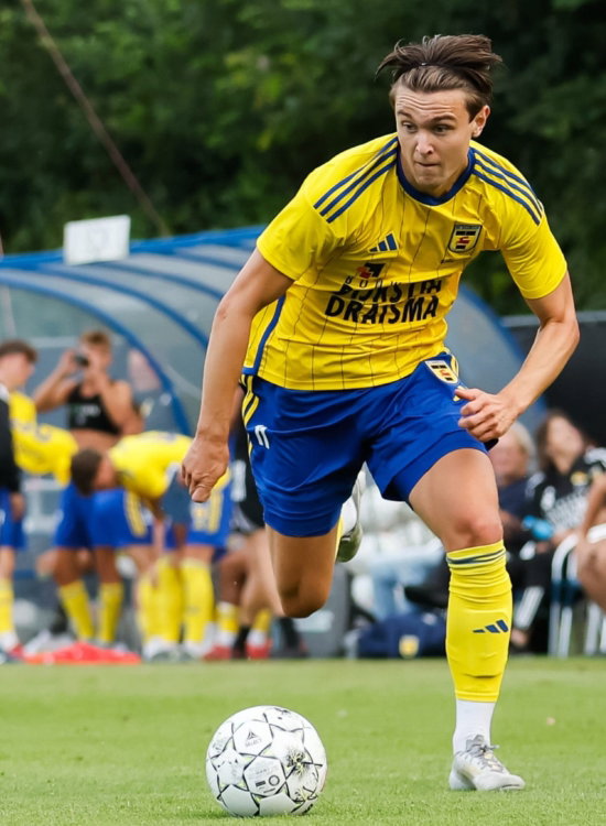 Jeugdspeler in geel sprint met de bal