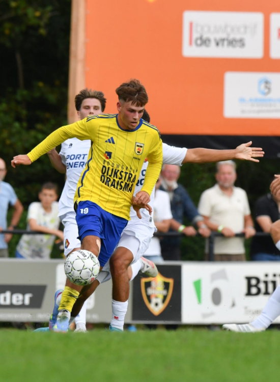 Jeugdspeler in geel tussen tegenstanders