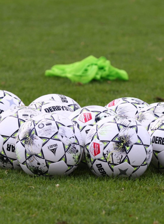 Groepje voetballen met een hesje op het veld