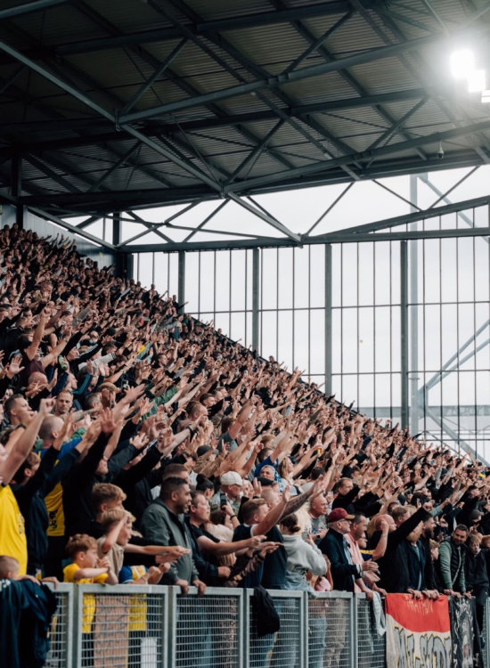 Volle tribune onder het stadiondak bij daglicht