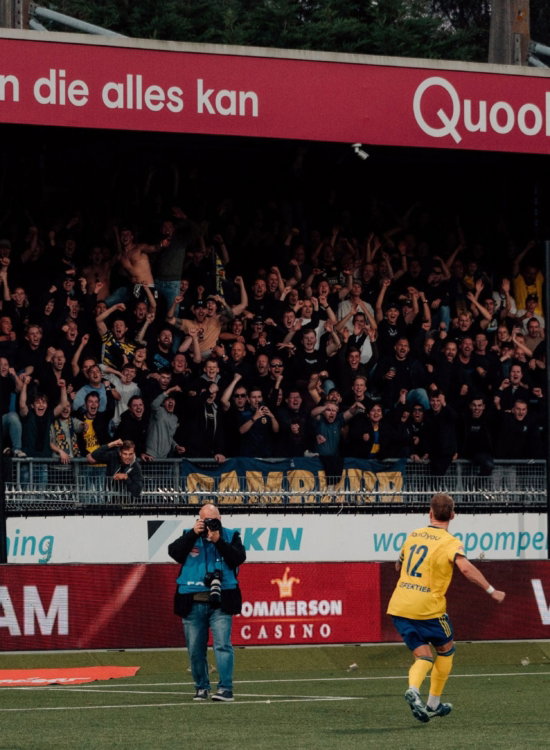 Speler langs de reclameborden voor de tribune