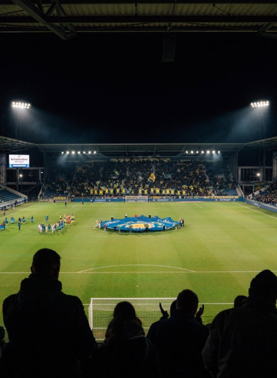 Supporters in silhouet voor het verlichte veld