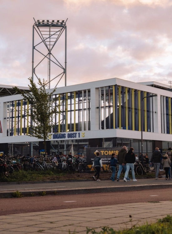 Supporters lopen naar het stadion bij avondrood