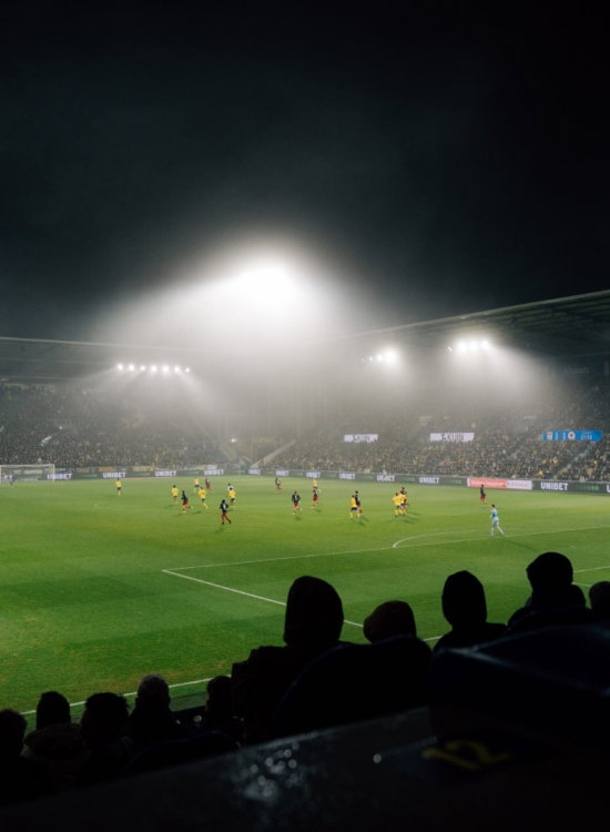 Supporters kijken naar een wedstrijd in de mist