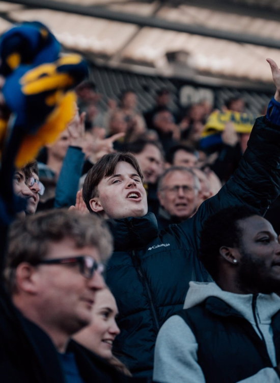 Supporters juichen met een vogelknuffel