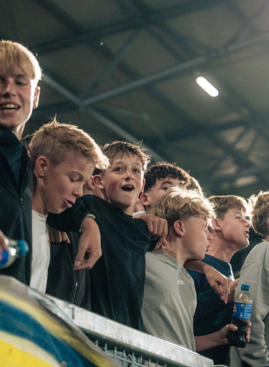 Jonge supporters zingen op de tribune