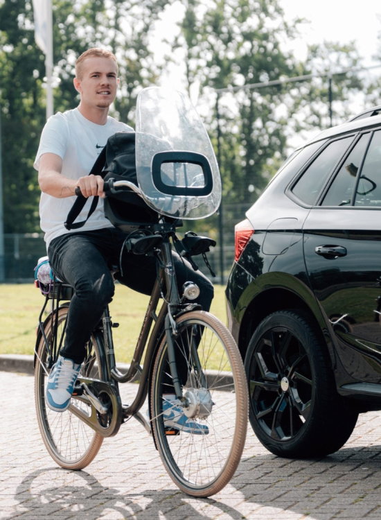 Fietser met camera naast een auto