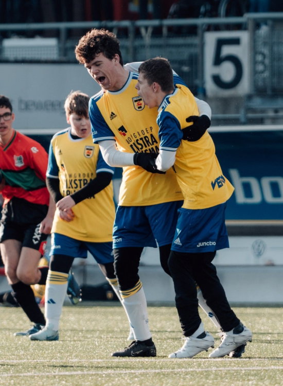 Jeugdspelers in hesjes bij de reclameborden