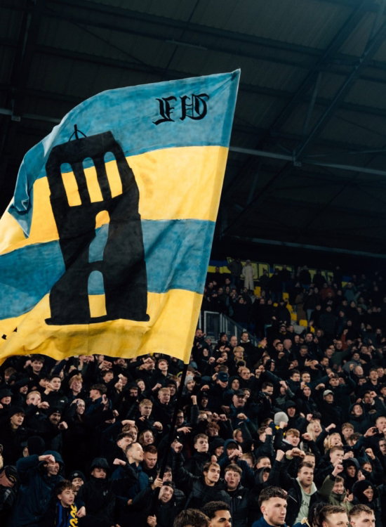 Geel-blauwe vlag met Oldehove op de tribune