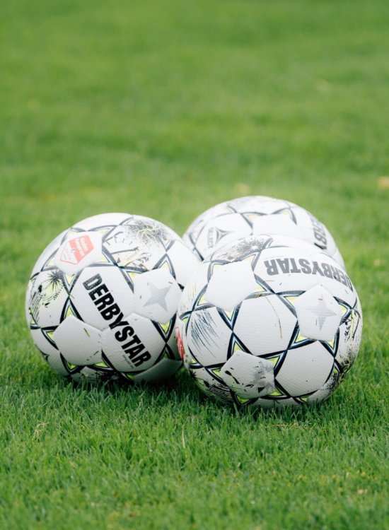 Twee voetballen op het gras in het stadion