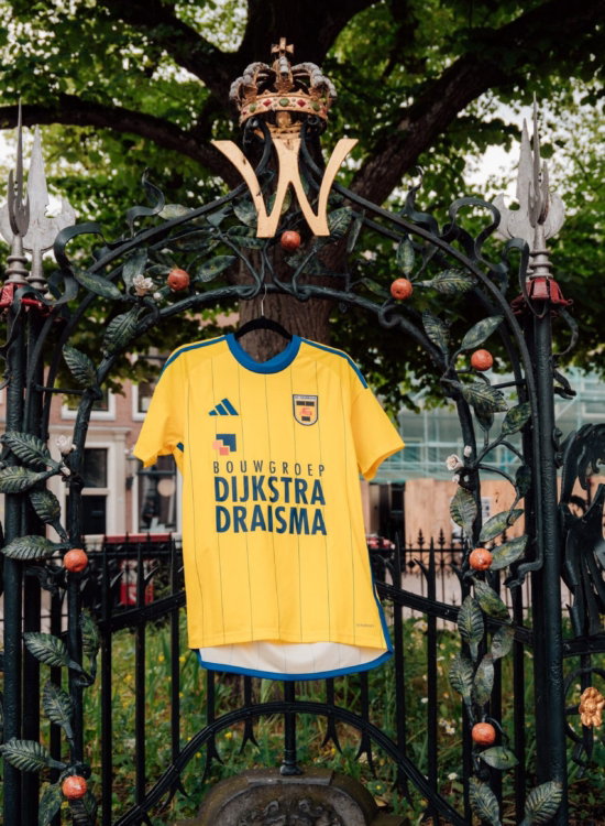 Geel Cambuur-shirt aan het hek bij een historisch gebouw