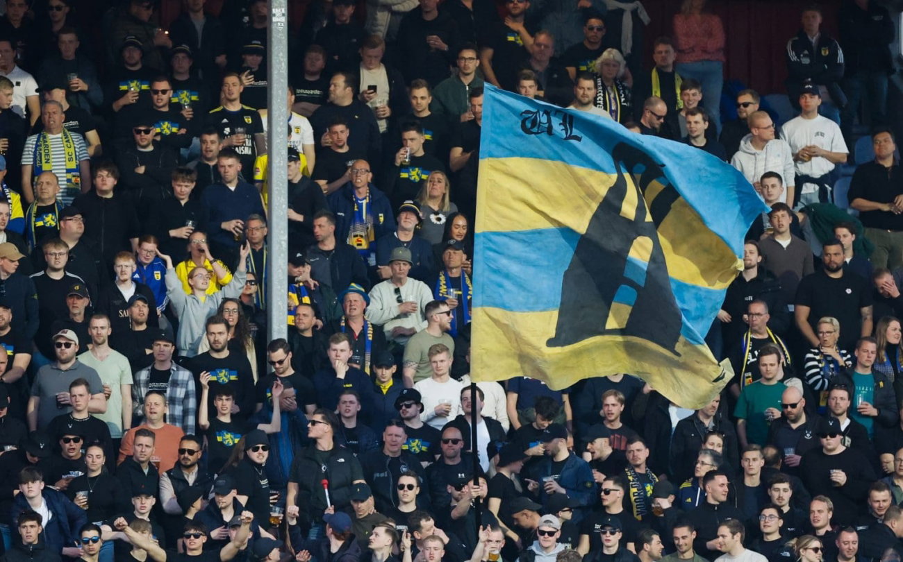 Volle tribune met geel-blauwe vlag