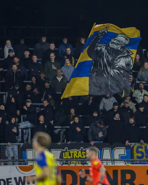 Grote vlag op de tribune bij een avondwedstrijd