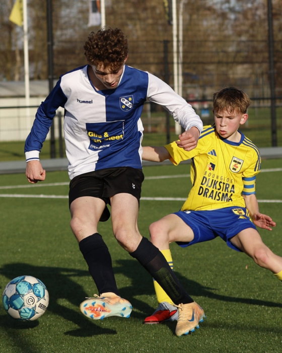 Jeugdspeler in geel in duel