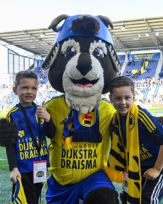 Mascotte met kinderen op het veld