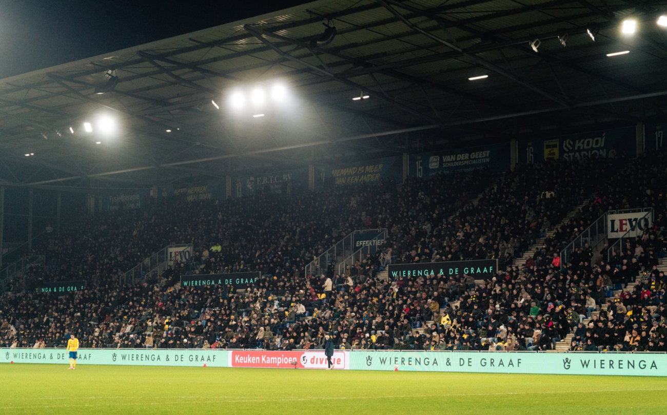 Volle tribune onder het licht bij een uitwedstrijd