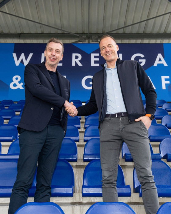 Partners geven elkaar een hand op de tribune