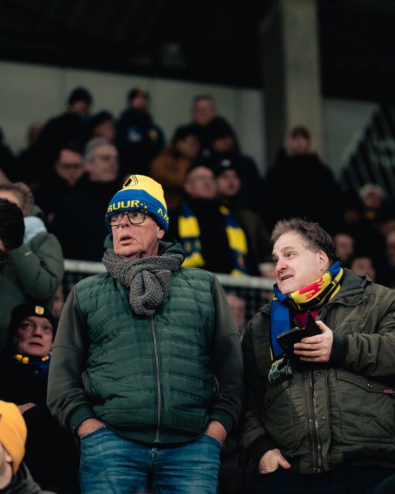 Supporters op de tribune bij een avondwedstrijd