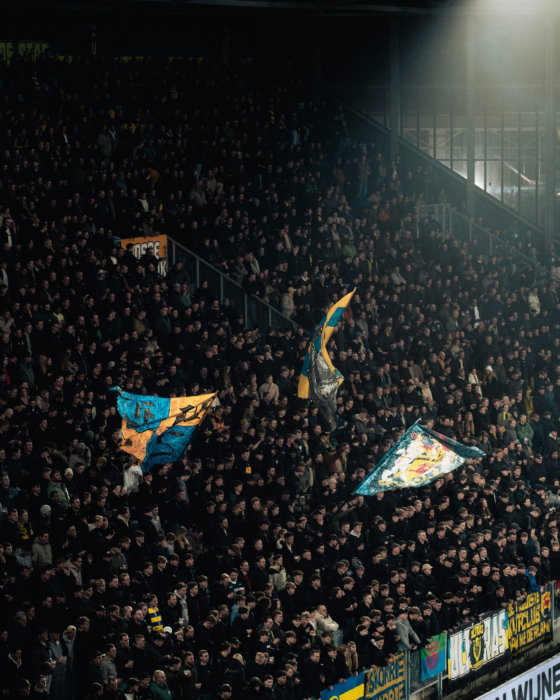 Volle tribune met vlaggen onder het licht
