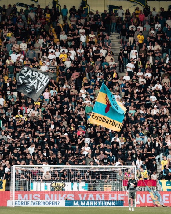 Volle tribune met vlaggen bij een thuiswedstrijd