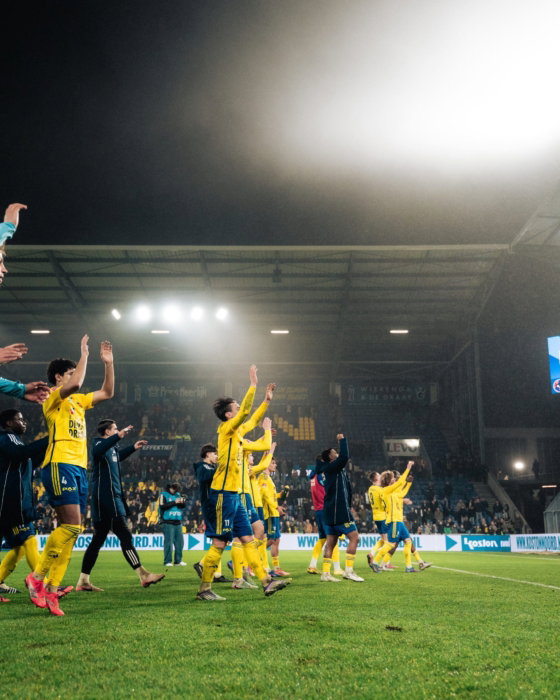 Spelers vieren onder het stadionlicht