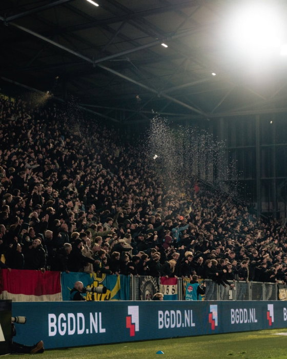 Volle tribune met reclameborden onder het licht