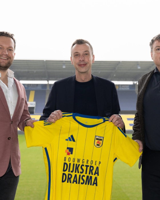 Drie partners met geel shirt in het stadion