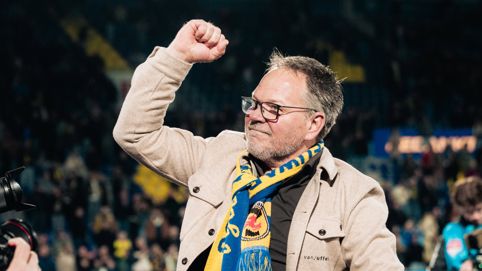 Supporter met sjaal juicht op het veld