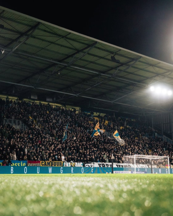 Volle tribune onder het licht bij een uitwedstrijd
