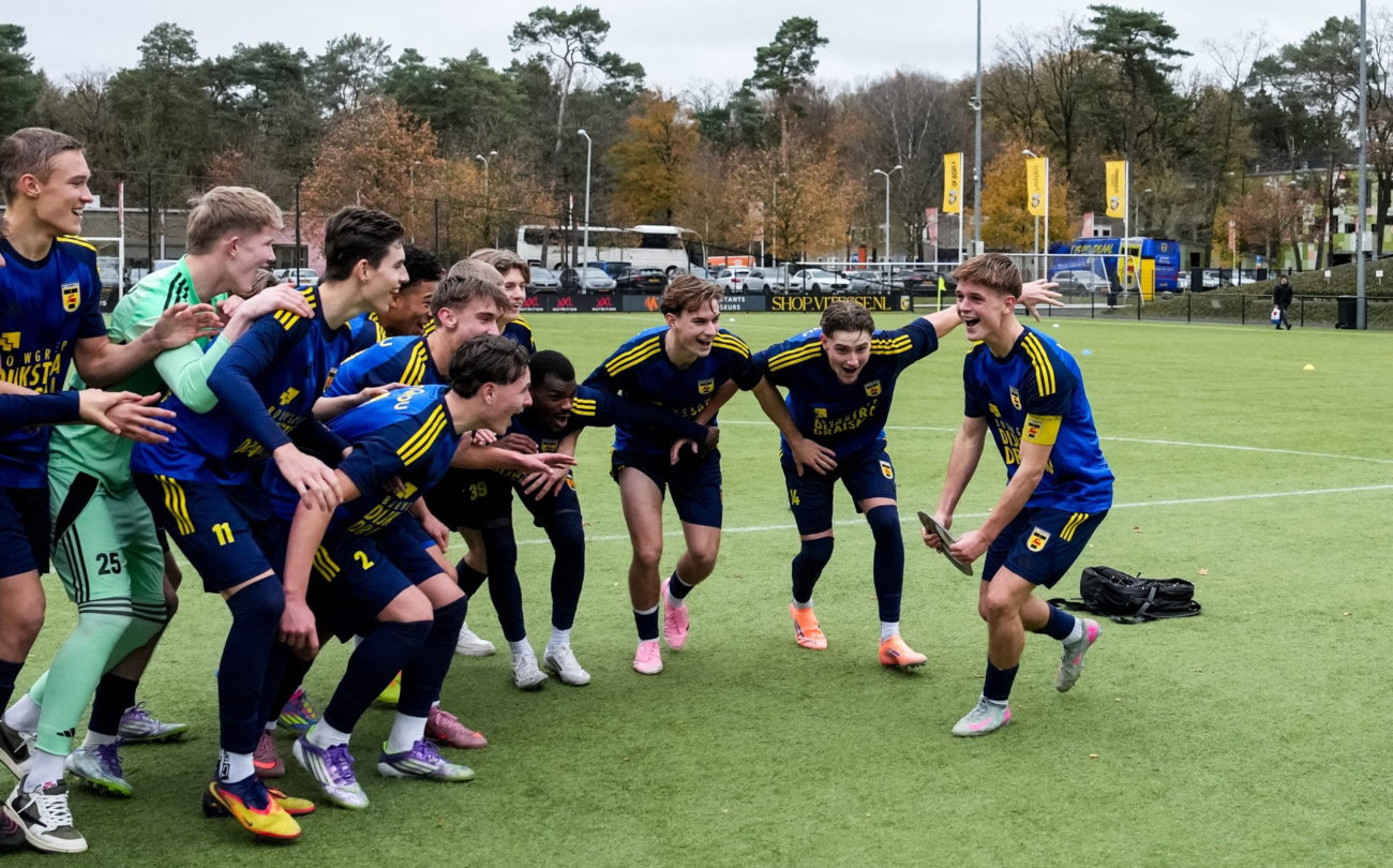 Jeugdspelers vieren met elkaar op het veld