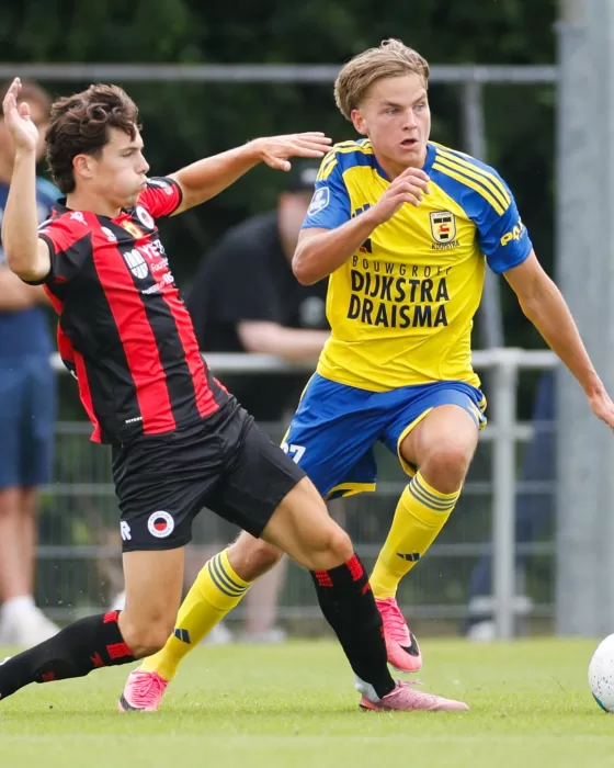 Jeugdspeler in duel met tegenstander in rood-zwart