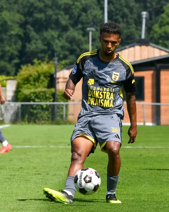 Jeugdspeler in grijs uitshirt dribbelt