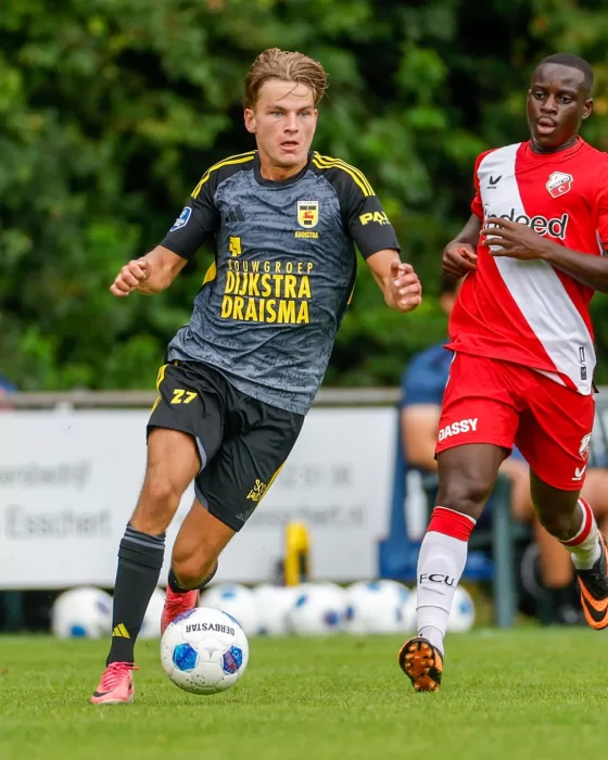 Jeugdspeler in grijs tegen ploeg in rood-wit