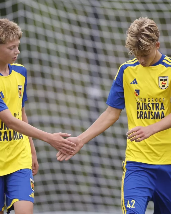 Twee jeugdspelers geven elkaar een hand