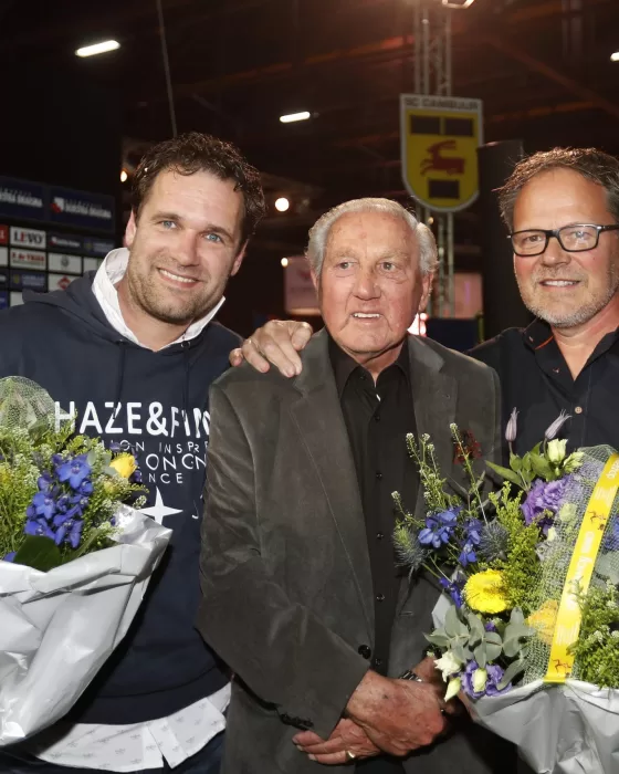 Drie mannen met bloemen bij een huldiging