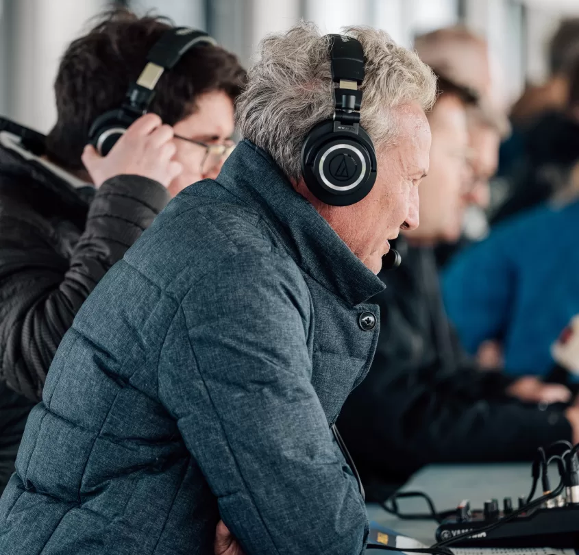 Commentatoren met koptelefoon op de perstribune