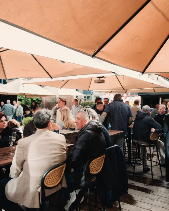 Gasten op het terras onder parasols