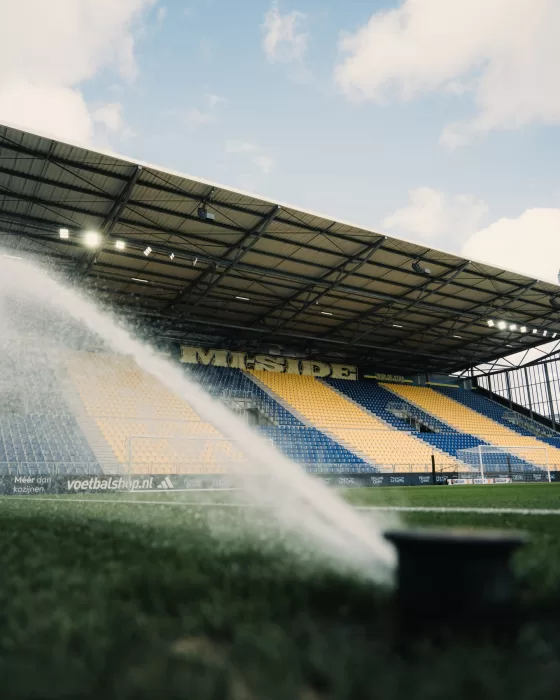 Sproeier besproeit het veld in het stadion
