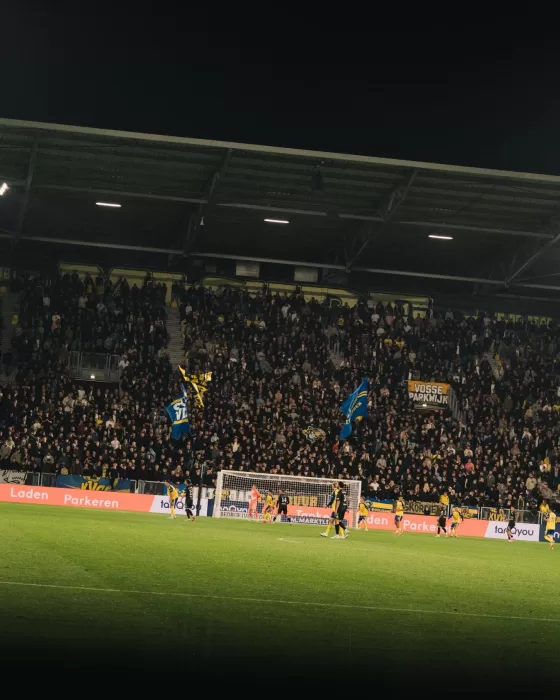 Volle tribune bij een avondwedstrijd