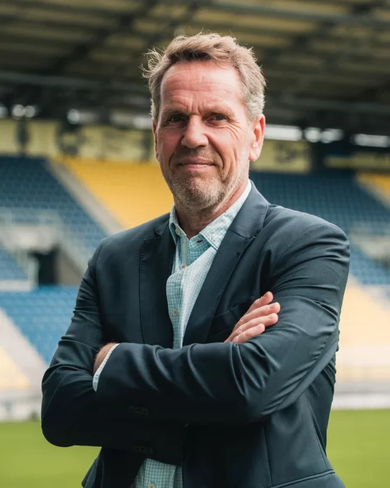 Partner staat met armen over elkaar in het stadion