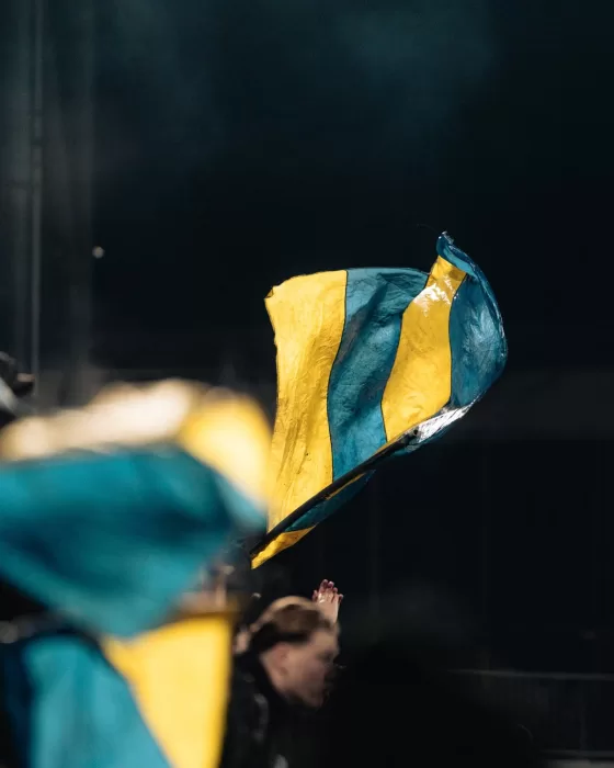 Supporter met pet en sjaal wijst naar de camera